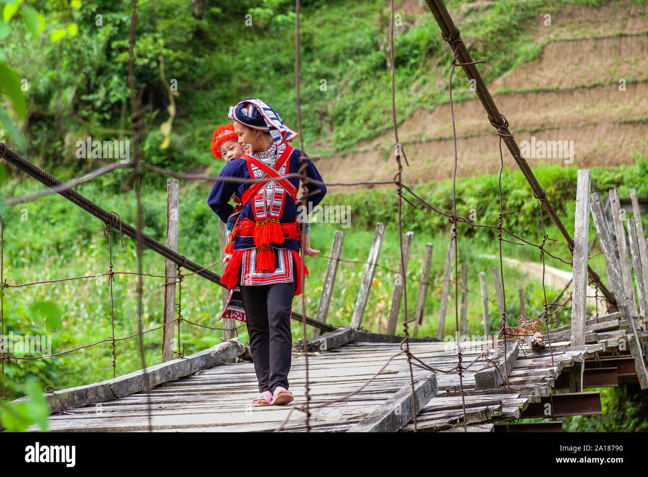Red Dao ethnic minority mother and baby (Dao Do), on a small suspension bridge in Hoang Su Phi, Ha Giang province, in the mountainous northwestern par Stock Photo