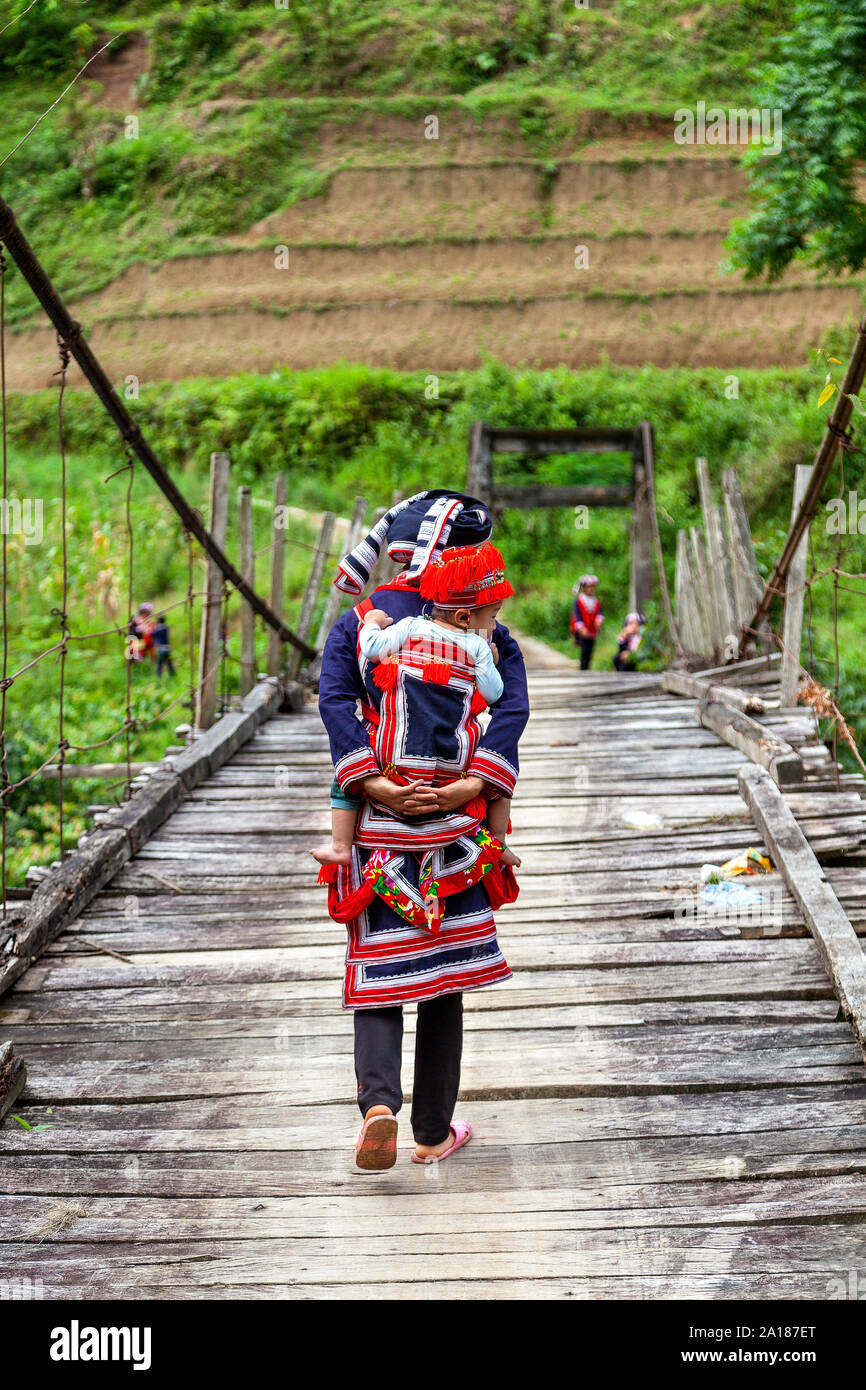 Red Dao ethnic minority mother and baby (Dao Do), on a small suspension bridge in Hoang Su Phi, Ha Giang province, in the mountainous northwestern par Stock Photo