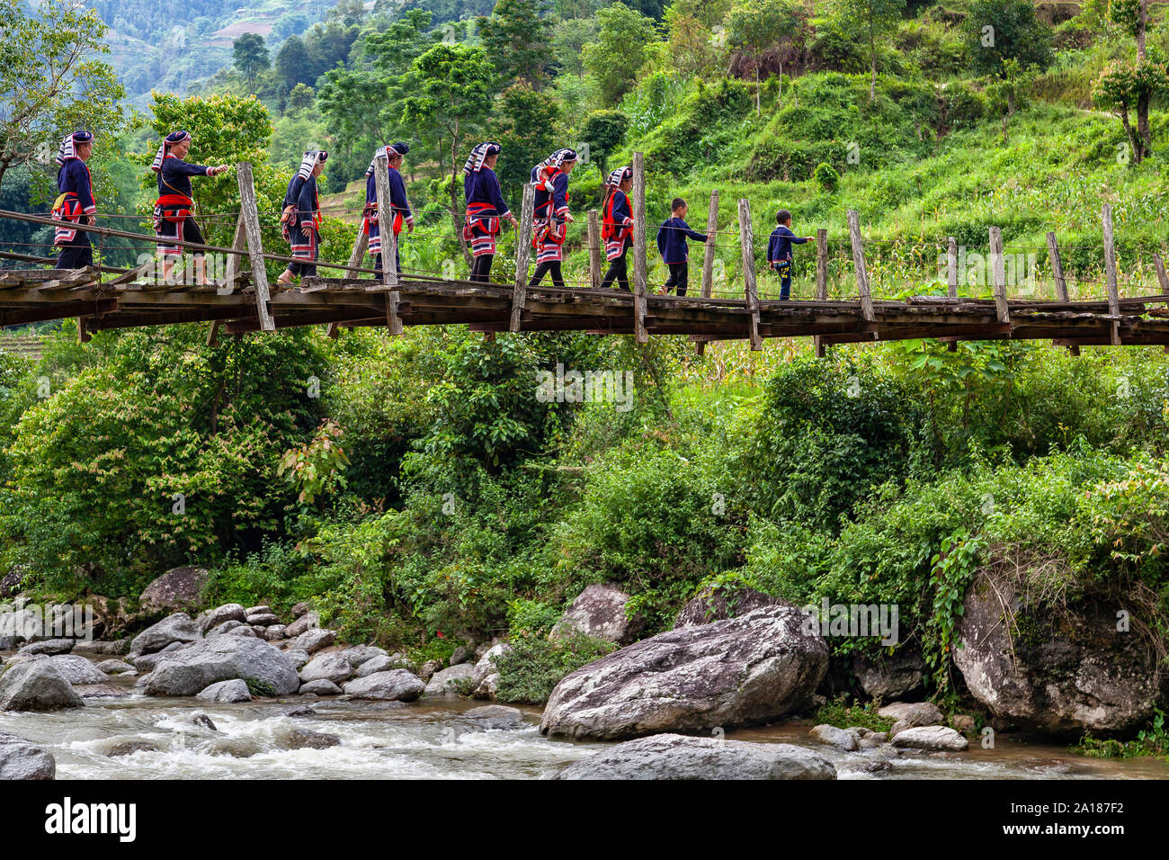 Red Dao ethnic minority people (Dao Do), on a small suspension bridge in Hoang Su Phi, Ha Giang province, in the mountainous northwestern part of Viet Stock Photo