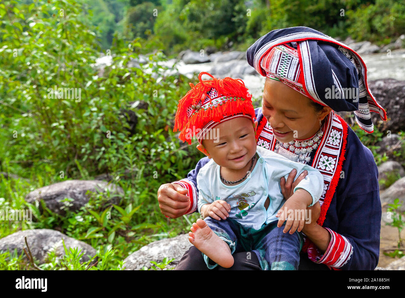 Red Dao ethnic minority woman and baby (Dao Do), by a river in Hoang Su Phi, Ha Giang province, in the mountainous northwestern part of Vietnam. Stock Photo