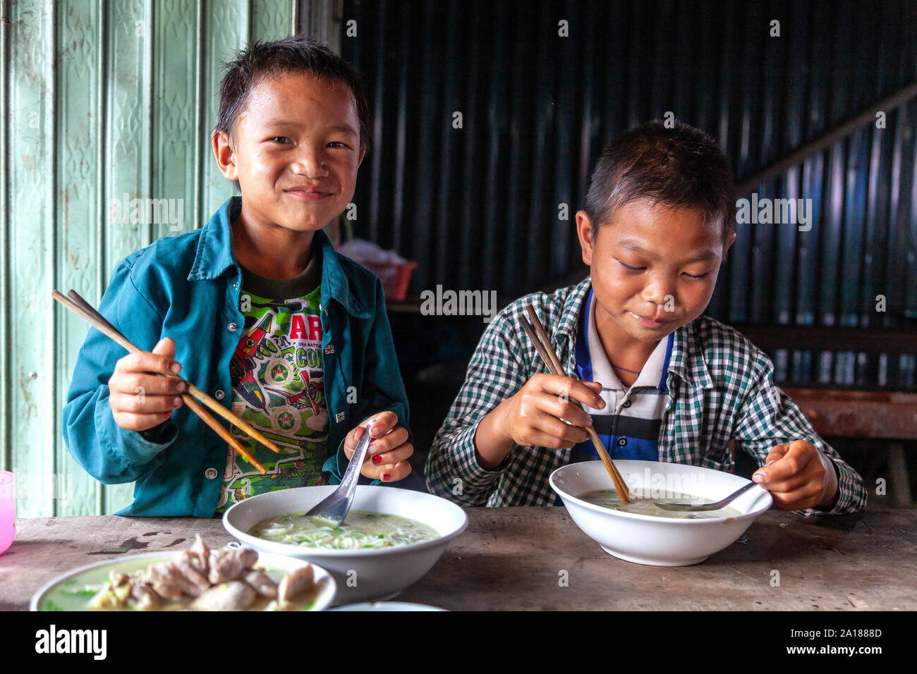 Boys having a meal in the small market town of Coc Pai in Ha Giang province, in the mountainous northwestern part of Vietnam. Stock Photo
