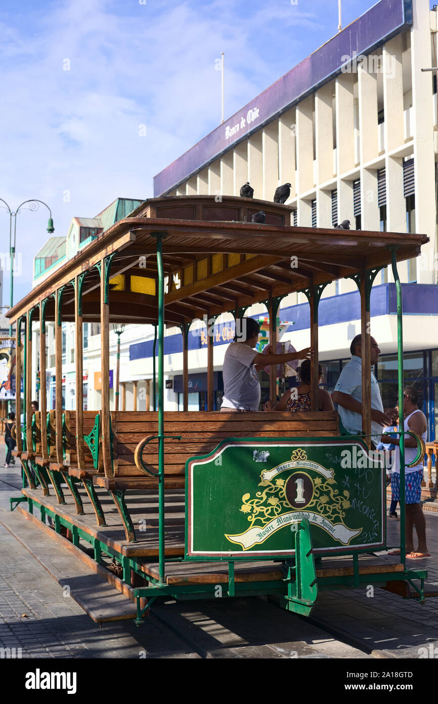 IQUIQUE, CHILE - JANUARY 22, 2015: Unidentified people getting off an old open tram waggon with wooden seats on Plaza Prat main square in Iquique Stock Photo