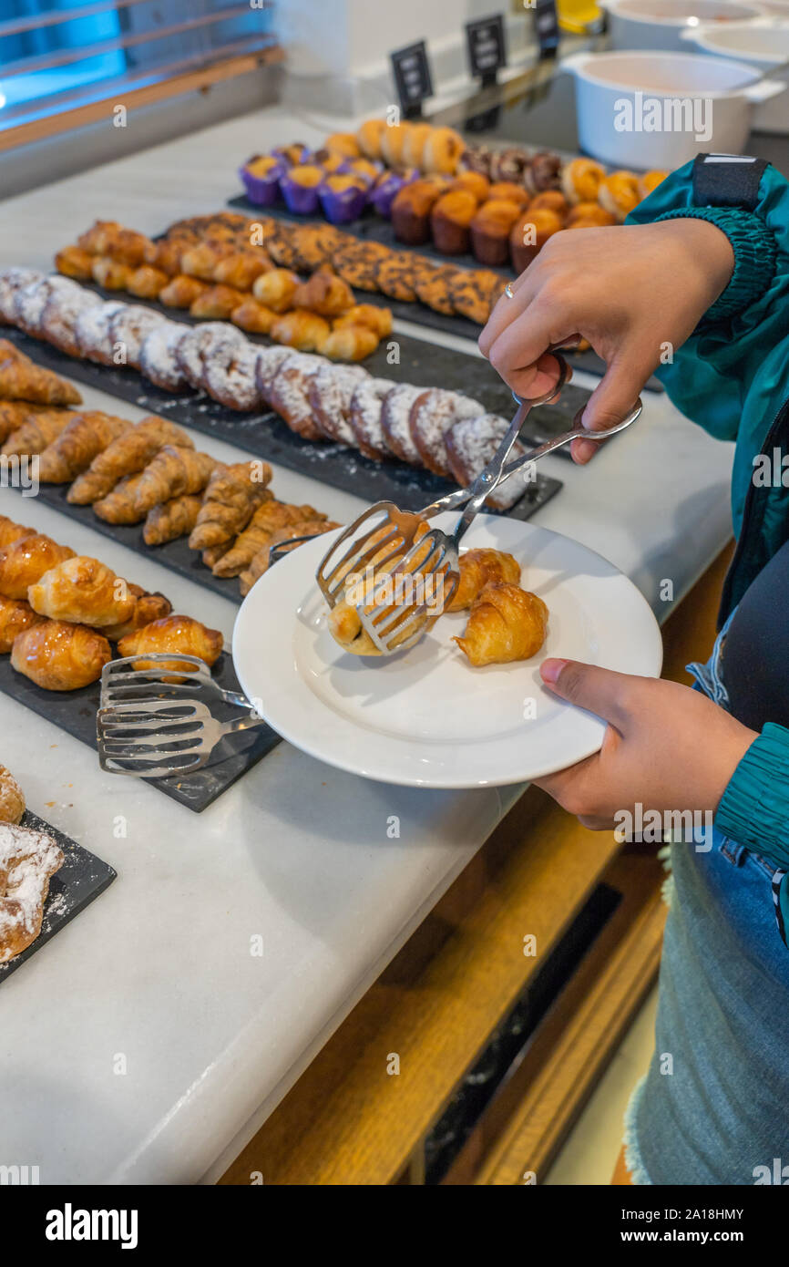 Woman hand using tongs picking croissant pastry at buffet meal Stock Photo  - Alamy