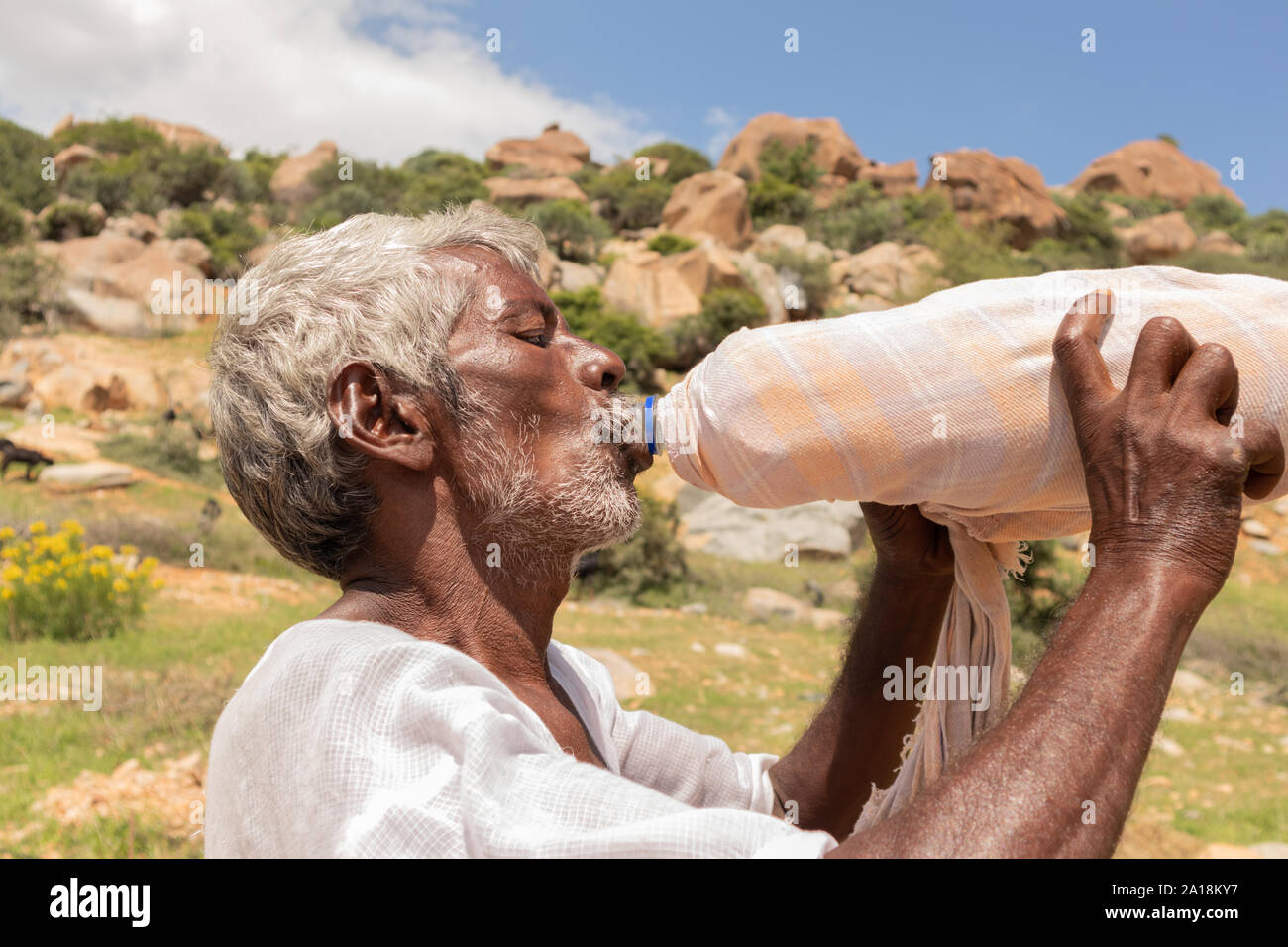 Maski, India 21 September, 2019 : Close up of Thirsty farmer man drinking water from plastic bottle covered with cloth for cooling during hot sunny Stock Photo