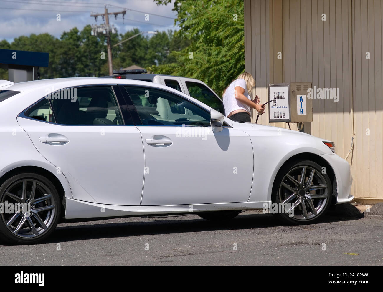 Woman trying to operate air pump so she can inflate her tires to the