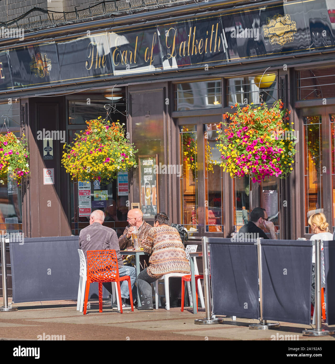 Customers sit outside the Earl of Dalkeith pub in the shopping centre at Kettering, Northamptonshire, England, on a sunny day. Stock Photo