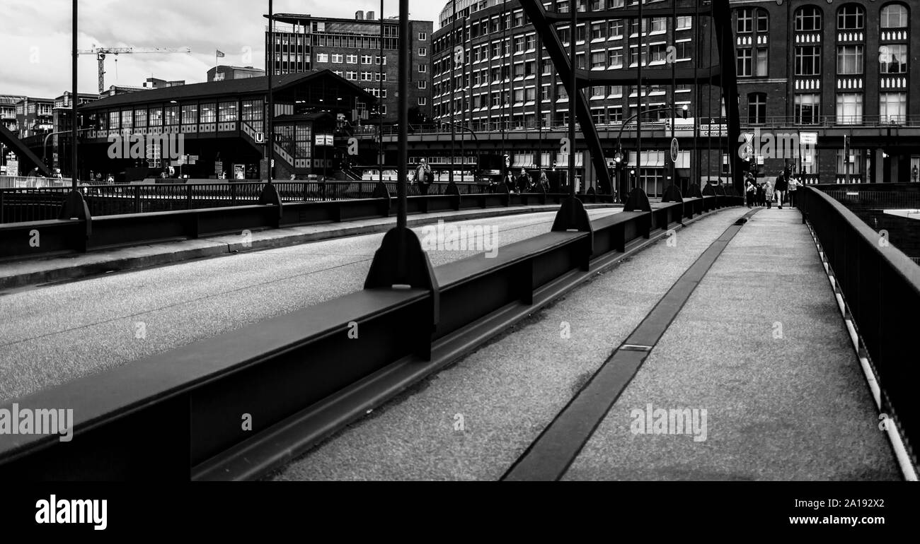 A black and white view over the bridge in Hamburg, Germany. Buildings, boardwalk and people in the background. Stock Photo