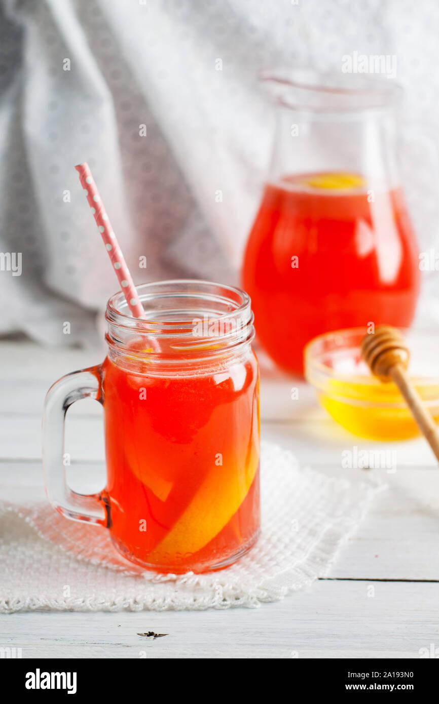 Strawberry lemonade with honey in mason jar and in jug on white wooden