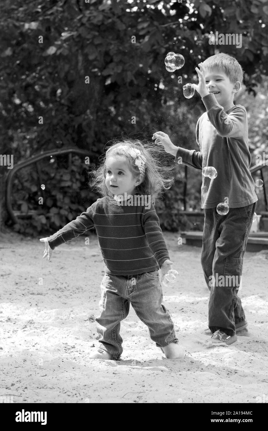 Children catching soap bubbles on summer playground Stock Photo