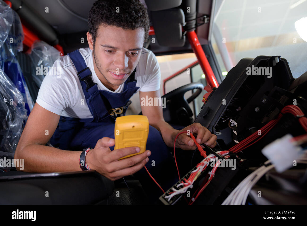 mechanic checking voltage of car battery in car service centre Stock Photo