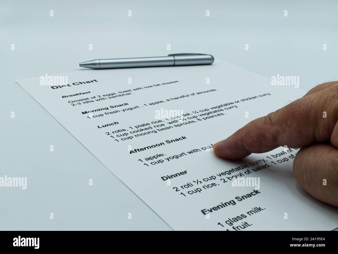 Checking and studying a diet chart, on white background. Stock Photo