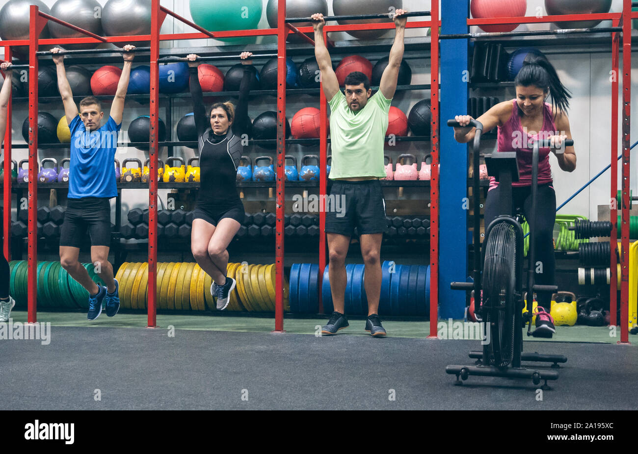 Athletes doing pull ups and air bike in the gym Stock Photo