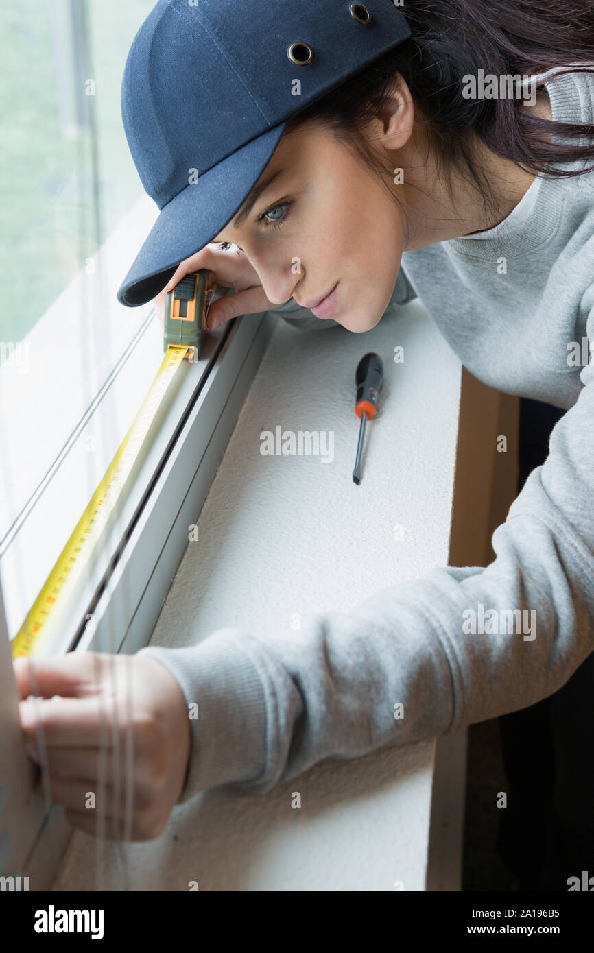 female builder making curtain rail measurements Stock Photo