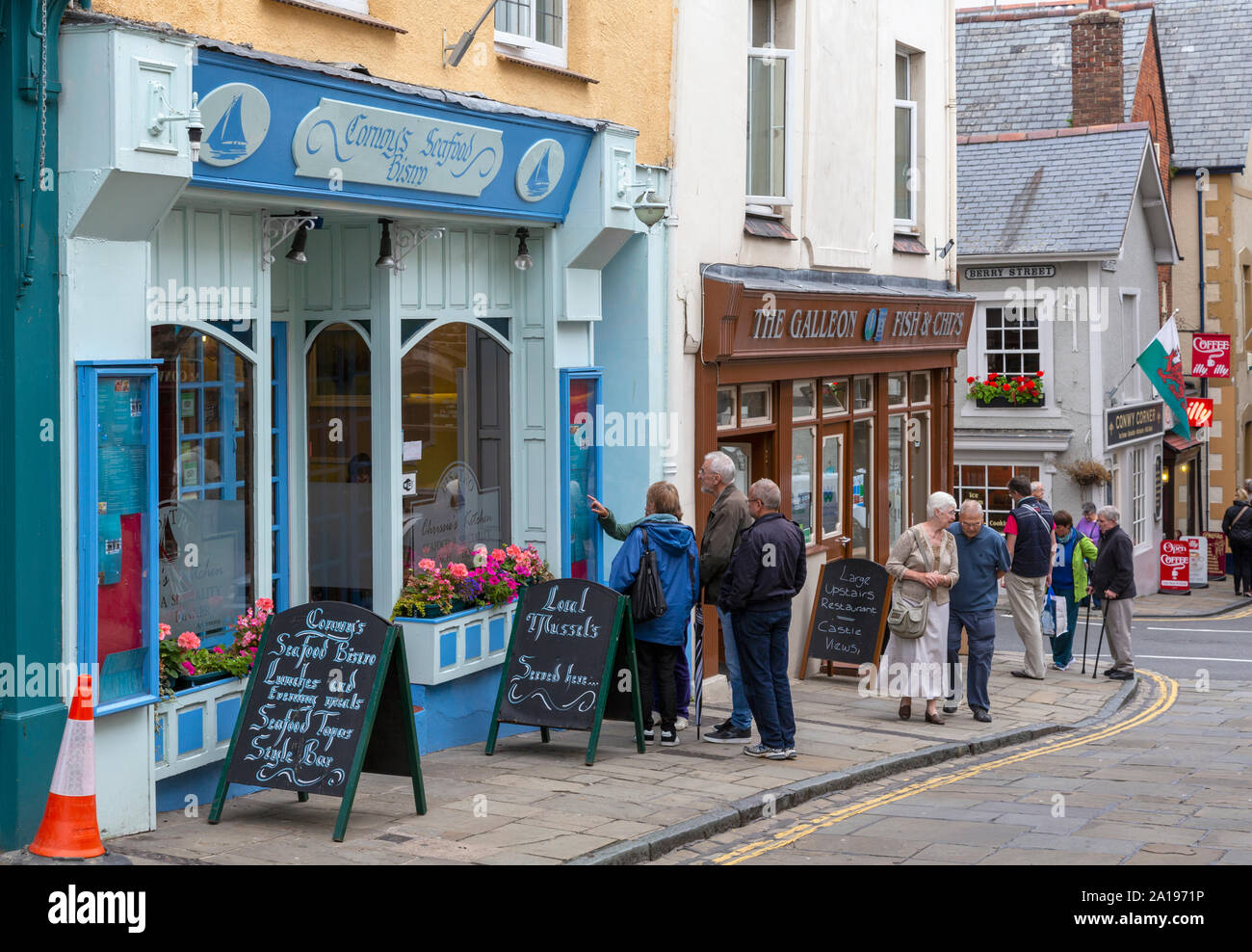 Pedestrians checking out seafood restaurants on High Street, Conwy or Conway, Conwy County, Wales, United Kingdom. Stock Photo