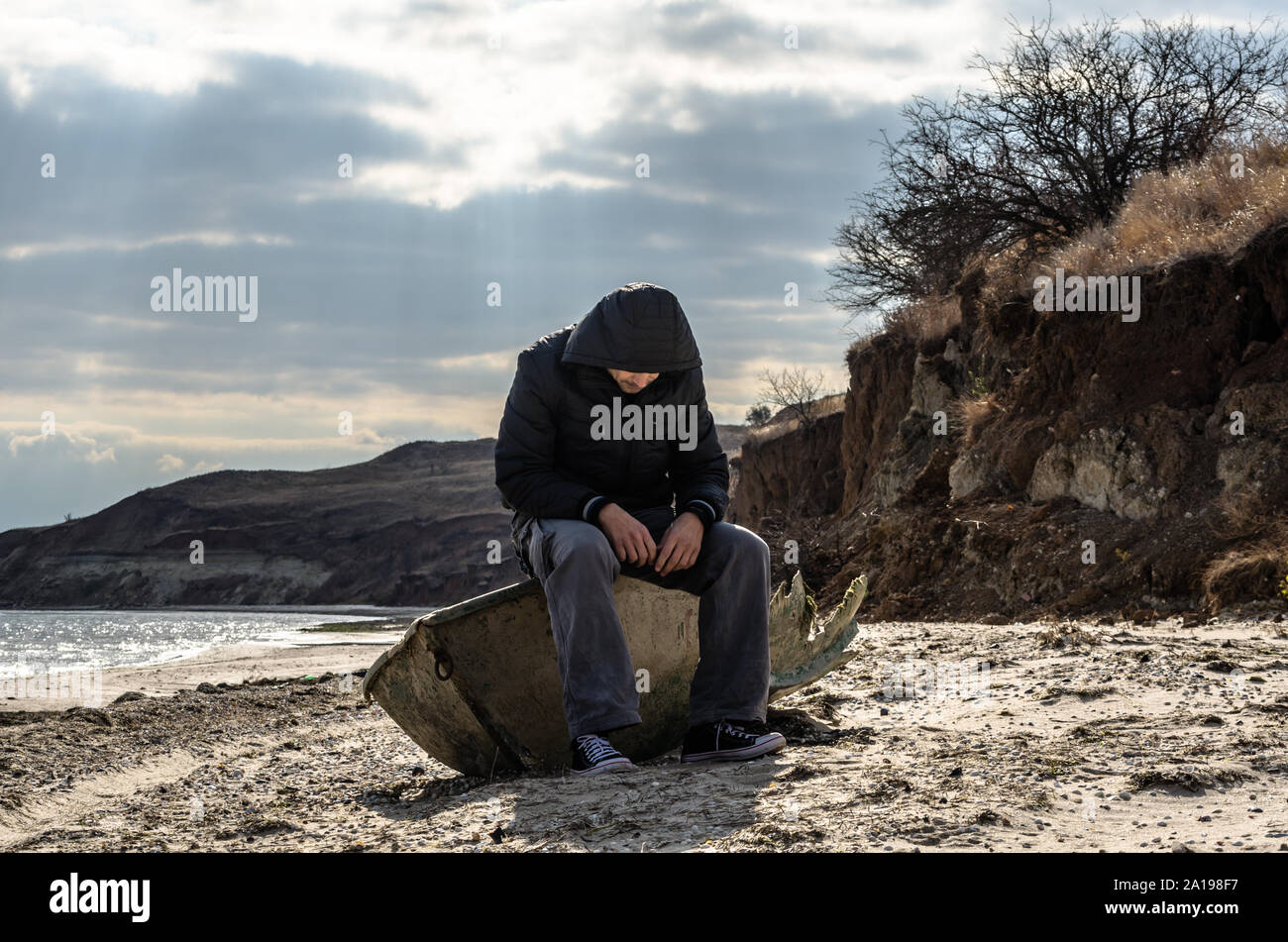 man in black sitting aboard a broken boat Stock Photo