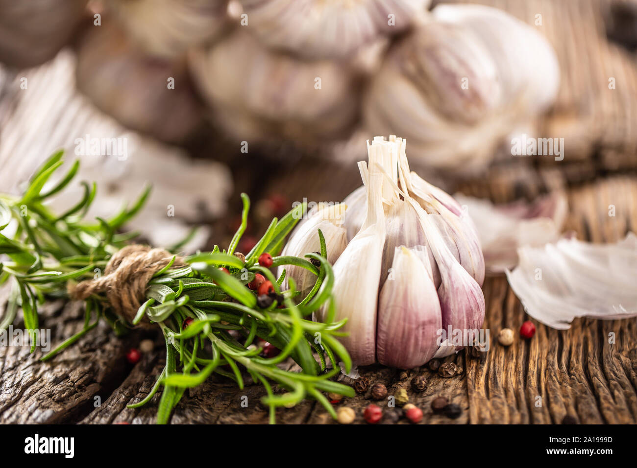 Garlic cloves bulb with fresh rosemary and spices on old wooden table Stock Photo