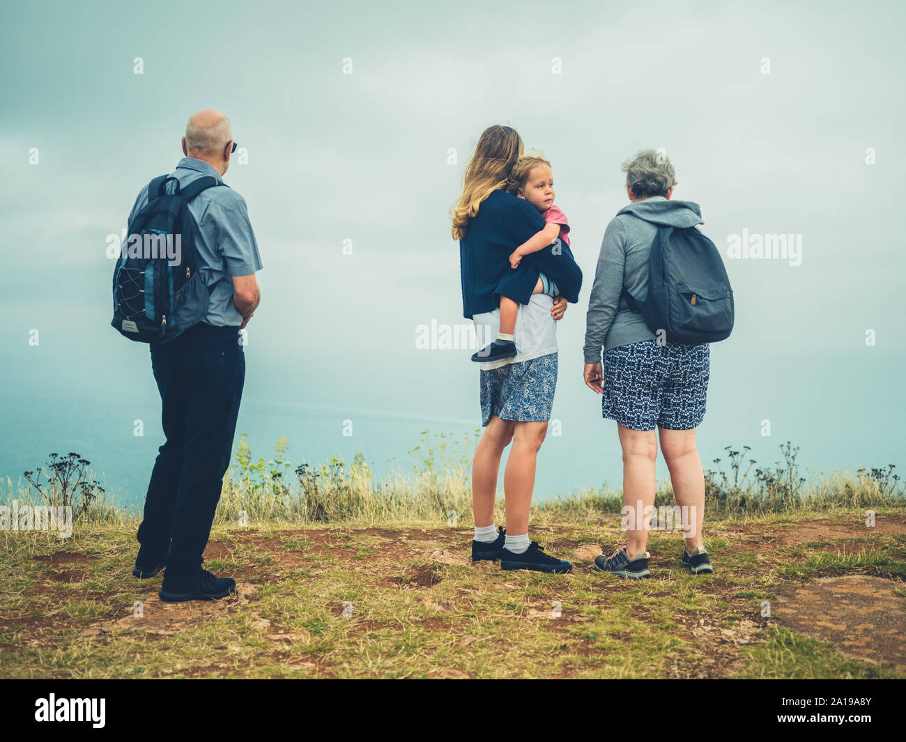 A real family of mother, toddler and grandparents in the fog by the sea Stock Photo