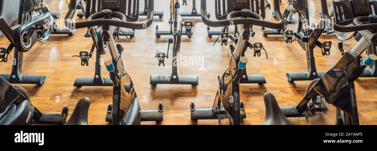 Aerobics spinning exercise bikes gym room with many in a row BANNER, LONG FORMAT Stock Photo