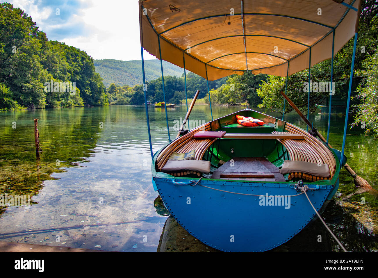 Small vessel in the water of a natural pristine lake with transparent surface. Stock Photo