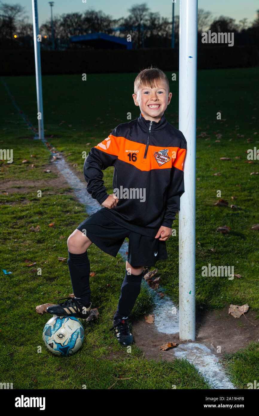 An eight year old boy wearing a soccer strip leaning against a goal post Stock Photo Alamy