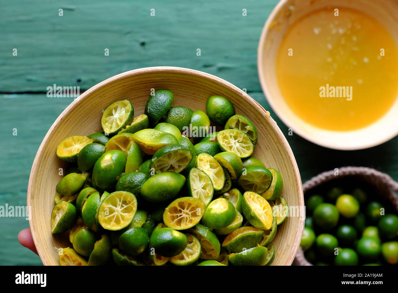 Top view people hand hold kumquat peel in green that squeezed out of