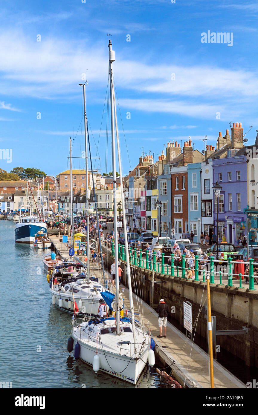 Yachts on the quay in the Old Harbour with colourful shops, restaurants and properties on Trinity Road, Weymouth, Jurassic Coast, Dorset, England, UK Stock Photo