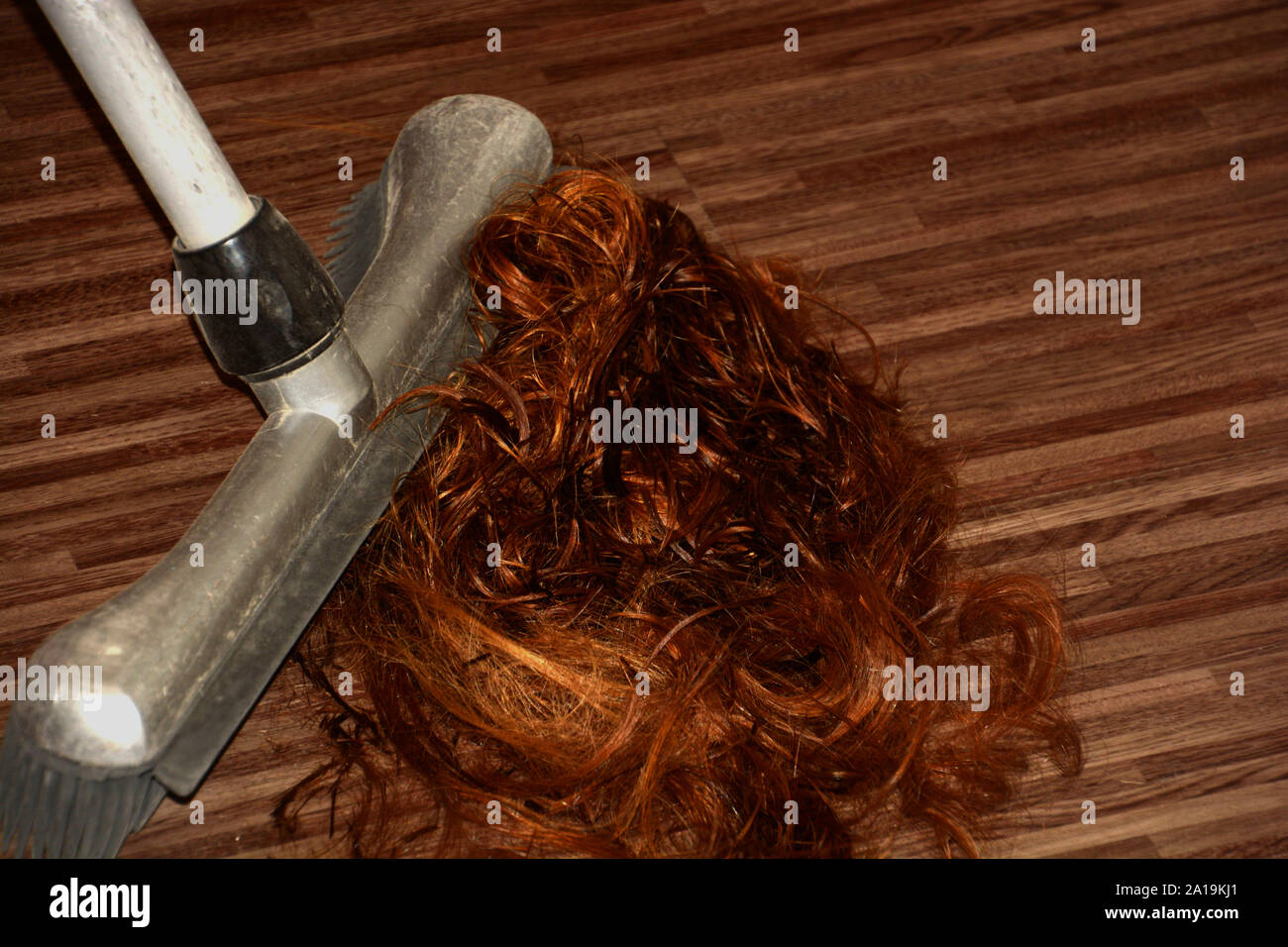 someone sweeping red hair clippings on floor closeup, hairdresser