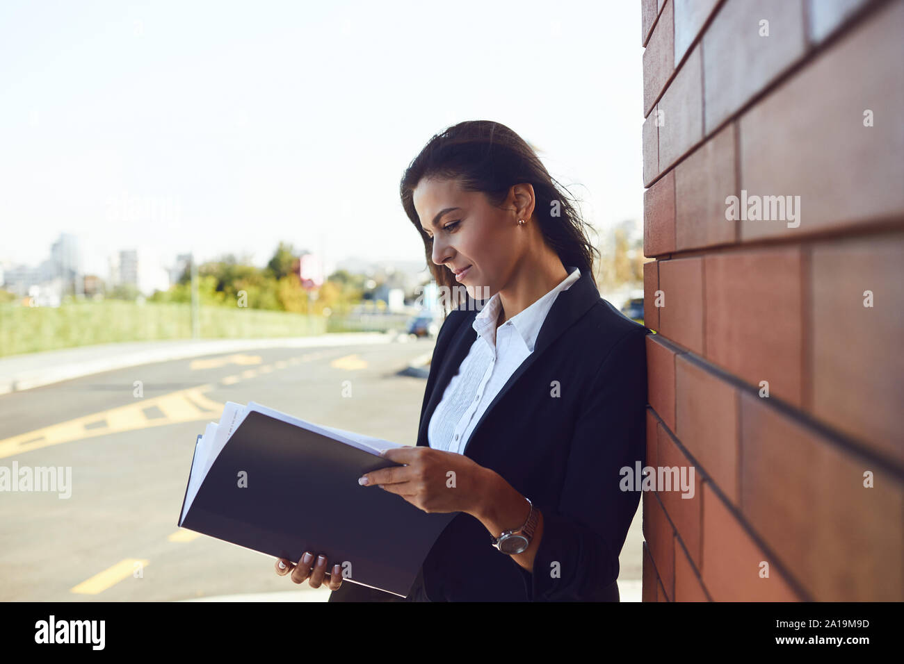 Serious businesswoman is reading documents while standing outdoors. Stock Photo