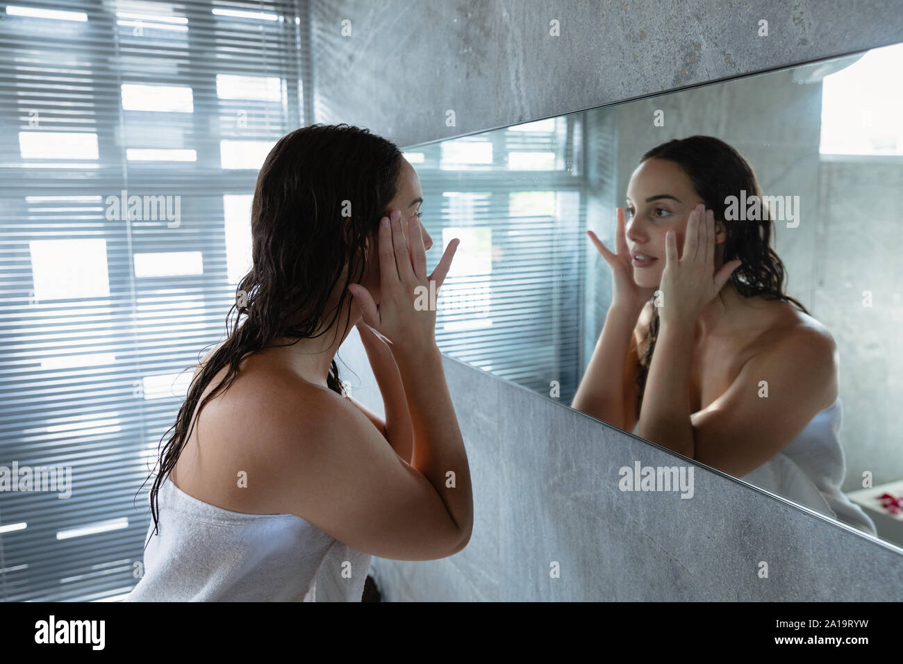 Young brunette woman looking in a mirror in a modern bathroom Stock ...