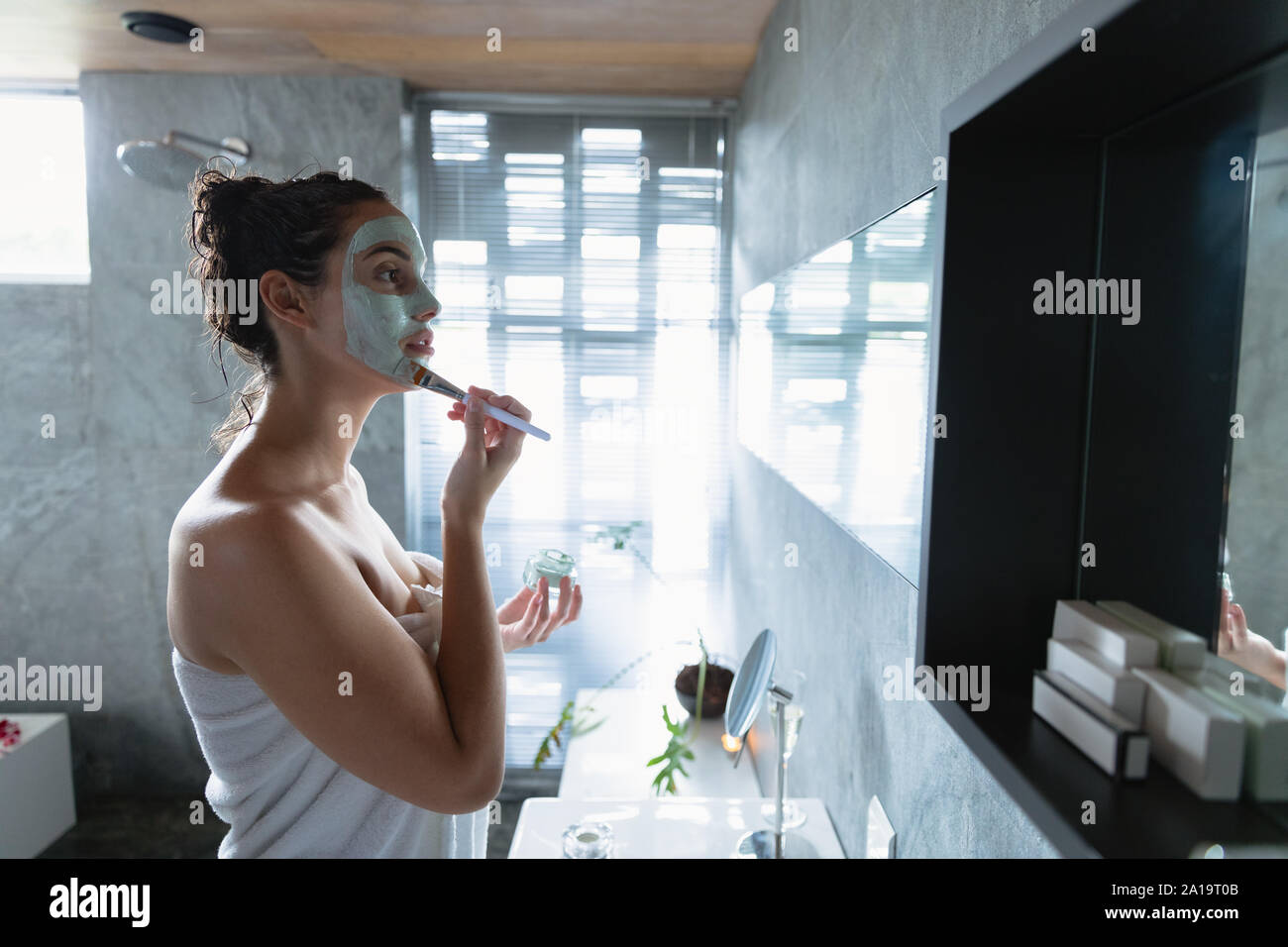 Young brunette woman applying face mask Stock Photo