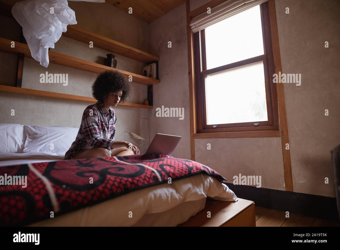 Young woman using laptop on her bed Stock Photo