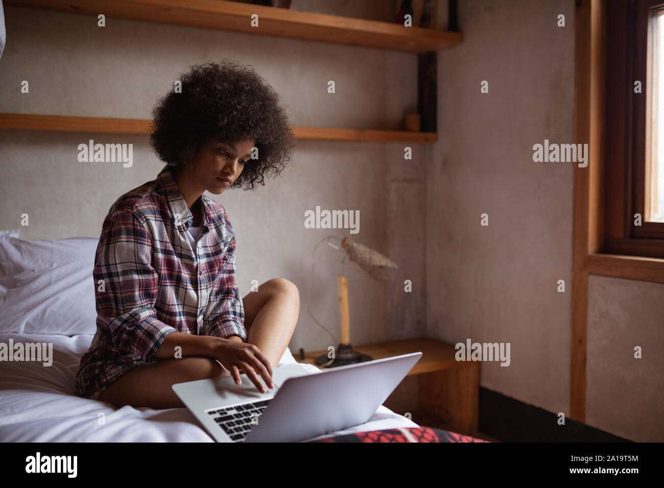 Young woman using laptop on her bed Stock Photo