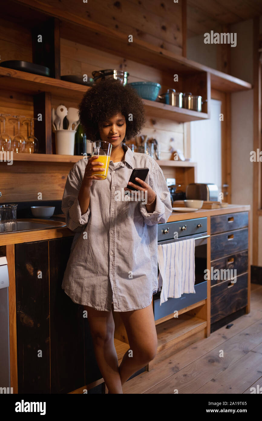 Young woman using smartphone in kitchen Stock Photo