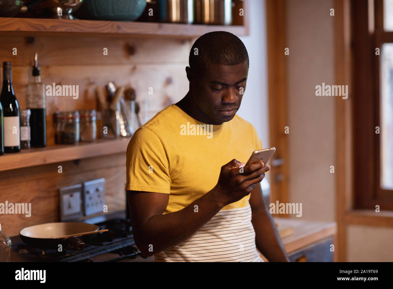 Young man using smartphone in kitchen Stock Photo
