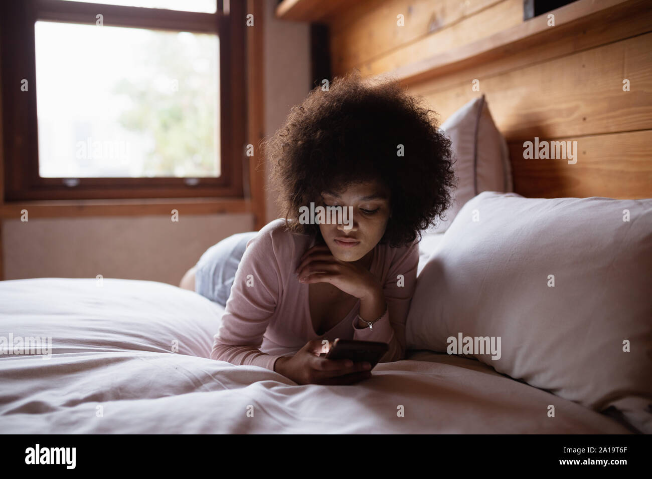 Young woman using smartphone in bed Stock Photo