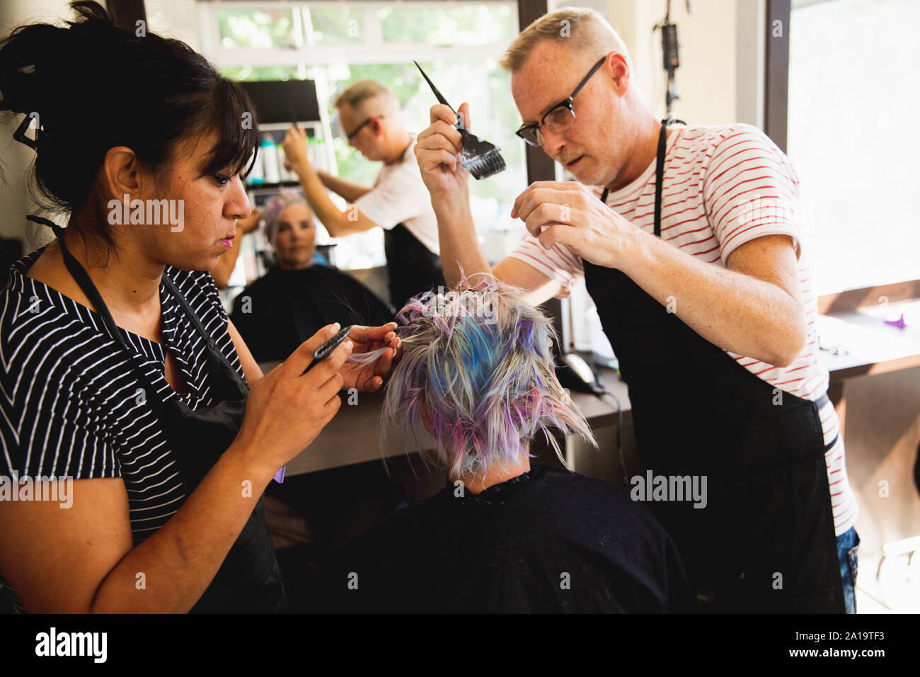 Hairdressers and female client in hair salon Stock Photo - Alamy