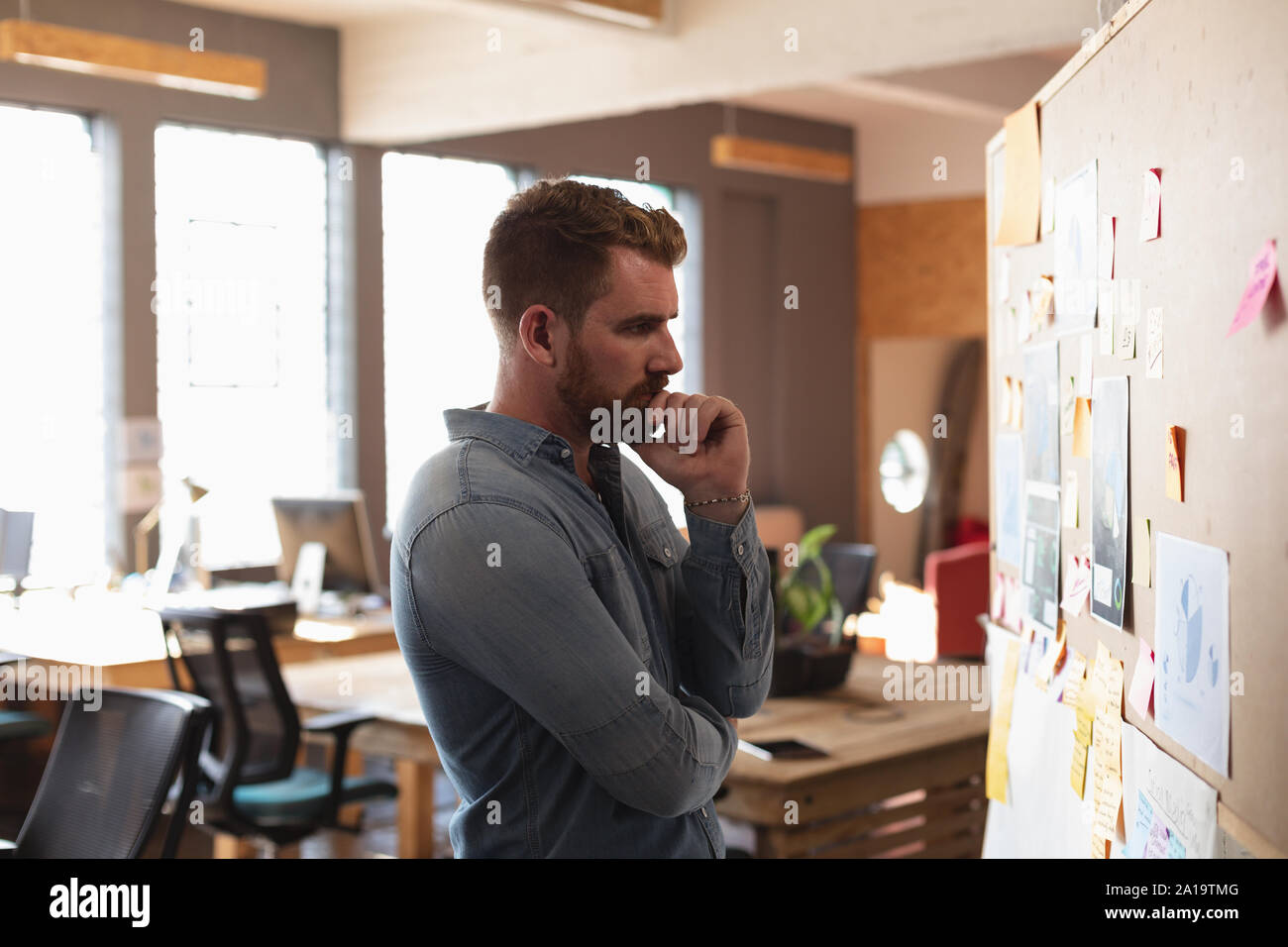 Young creative professional man working in a sunlit office Stock Photo