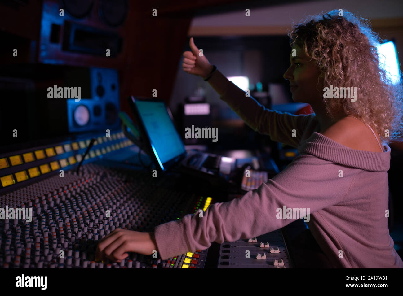Female music producer working at the mixing desk in a sound studio