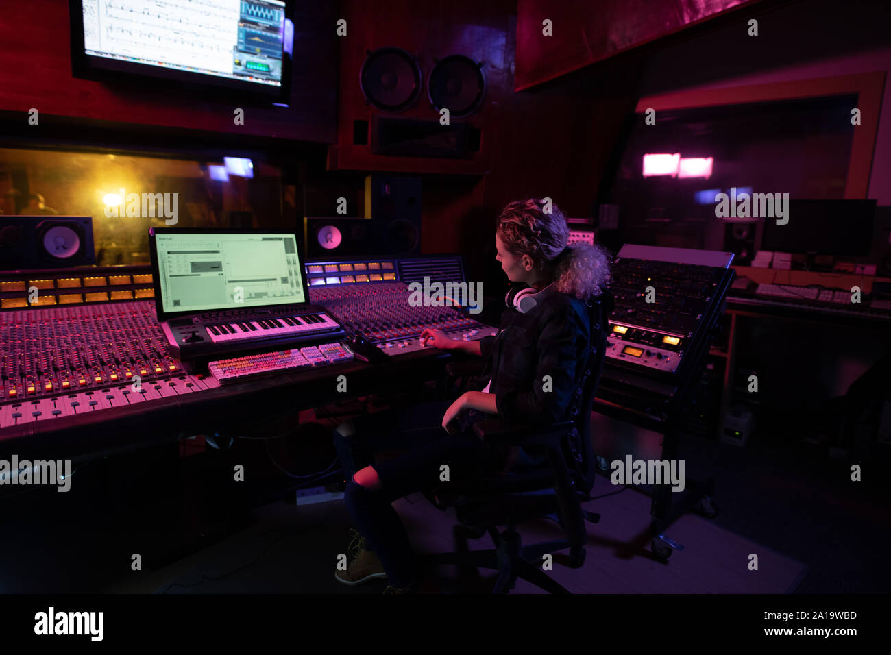 Female music producer working at the mixing desk in a sound studio