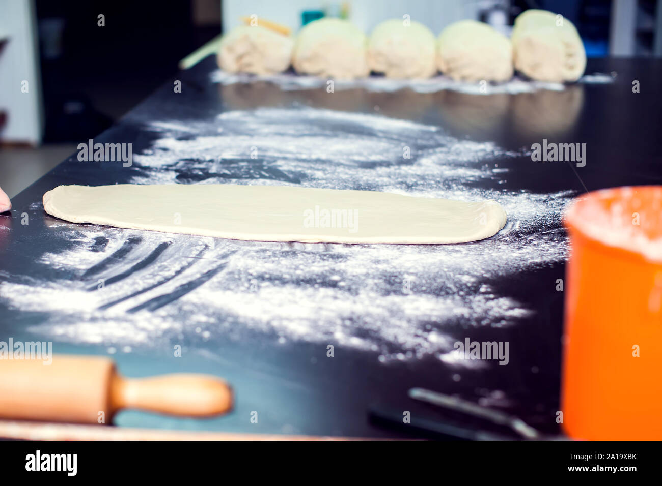 A chef rolls out the doughon on black table. Stock Photo