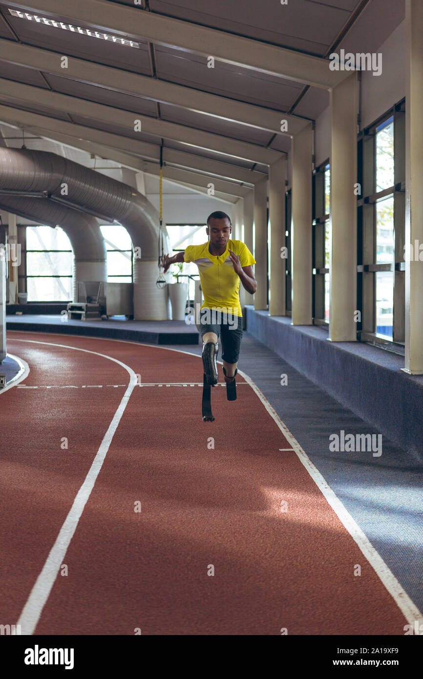 Disabled African American male athletic running on sports track in fitness center Stock Photo