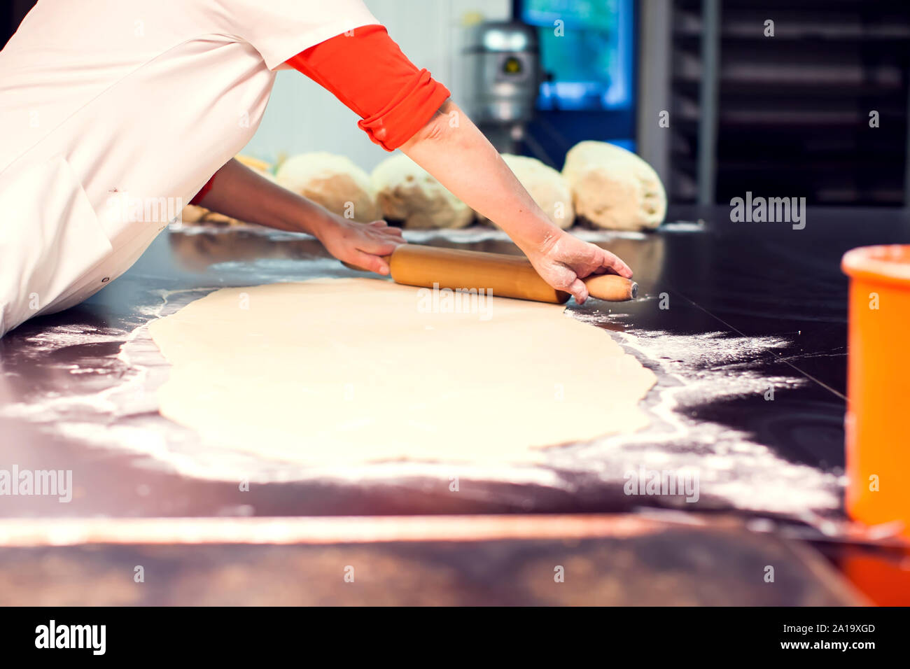 A chef rolls out the doughon on black table. Stock Photo