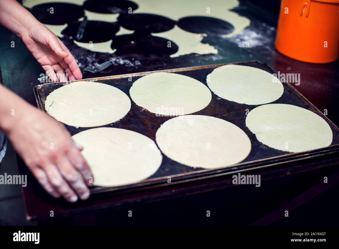 A chef rolls out the doughon on black table. Stock Photo