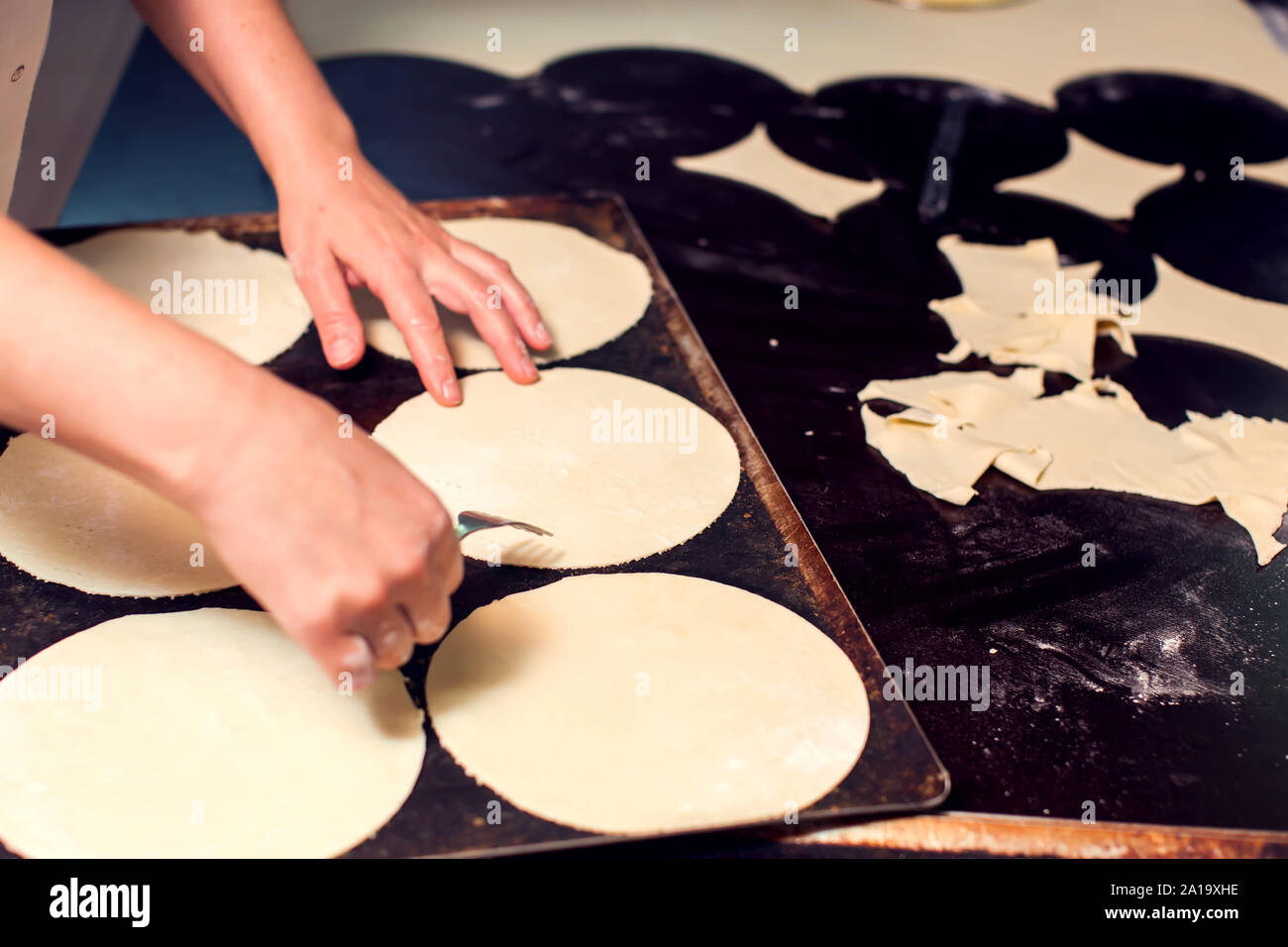 A chef rolls out the doughon on black table. Stock Photo