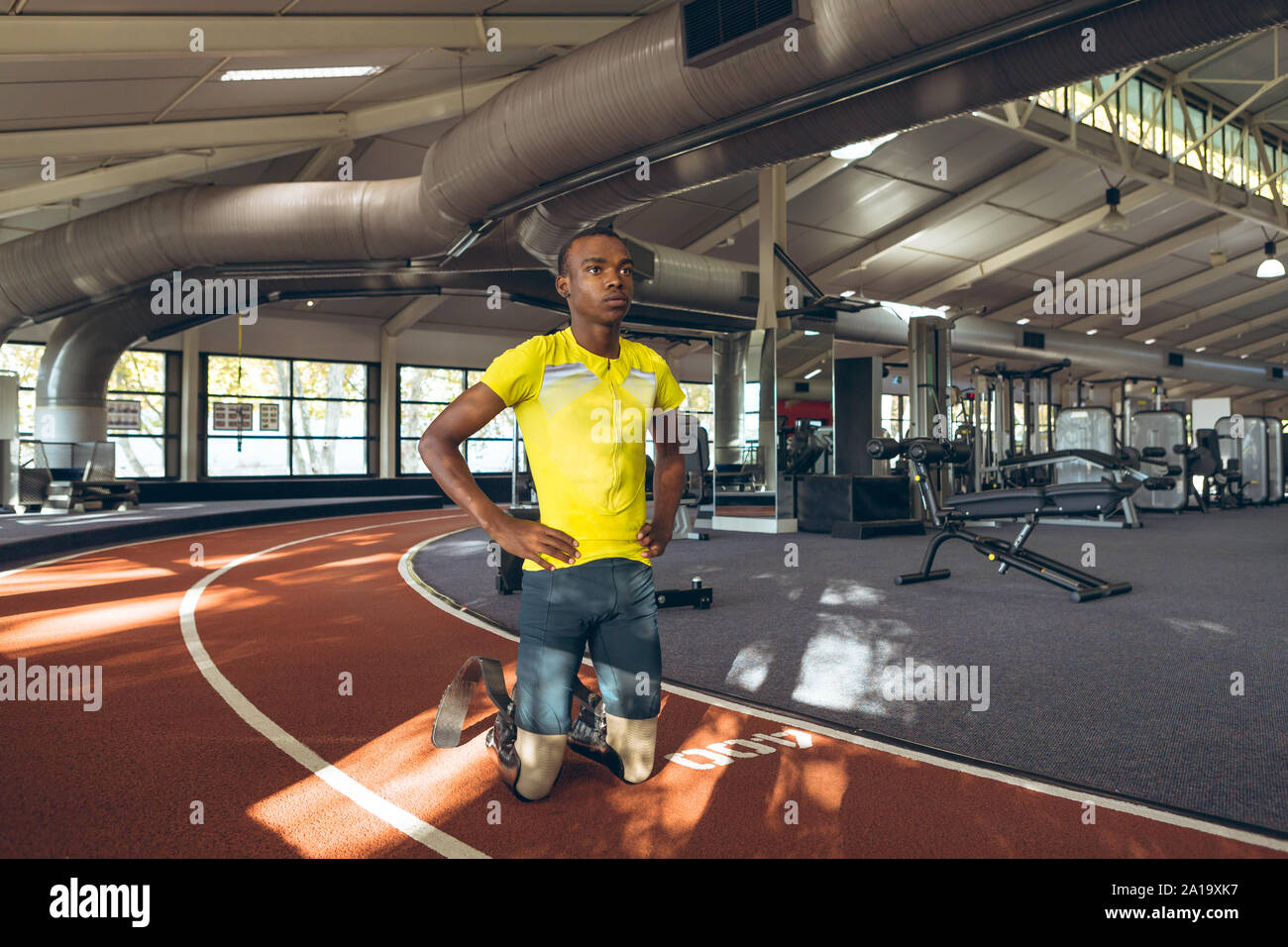 Disabled African American male kneeling with hands on hip in fitness center Stock Photo