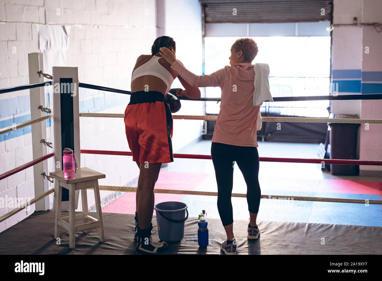 Trainer consoling female boxer in boxing ring at fitness center Stock ...