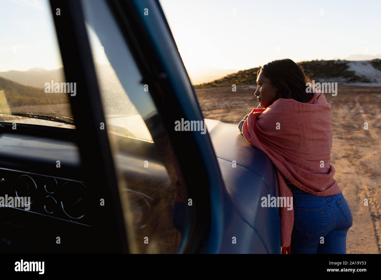 Young woman leaning on a pick-up truck during a stop off on a road trip Stock Photo