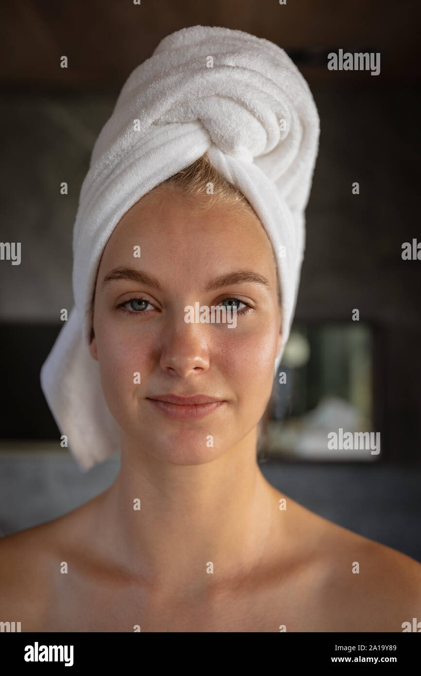Young blonde woman in a hotel bathroom with her hair wrapped in a towel Stock Photo