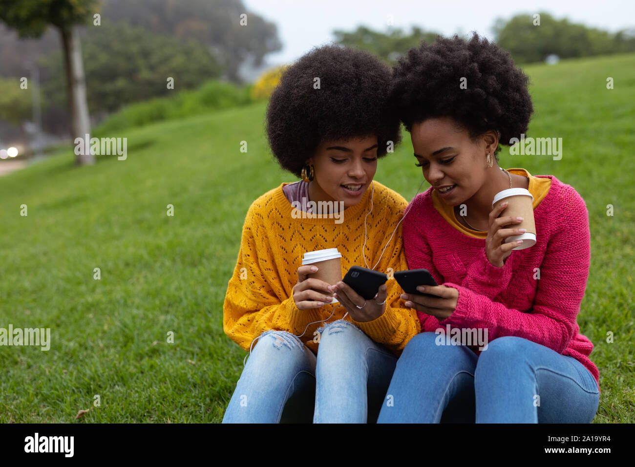 Two young women using smartphones outdoors Stock Photo