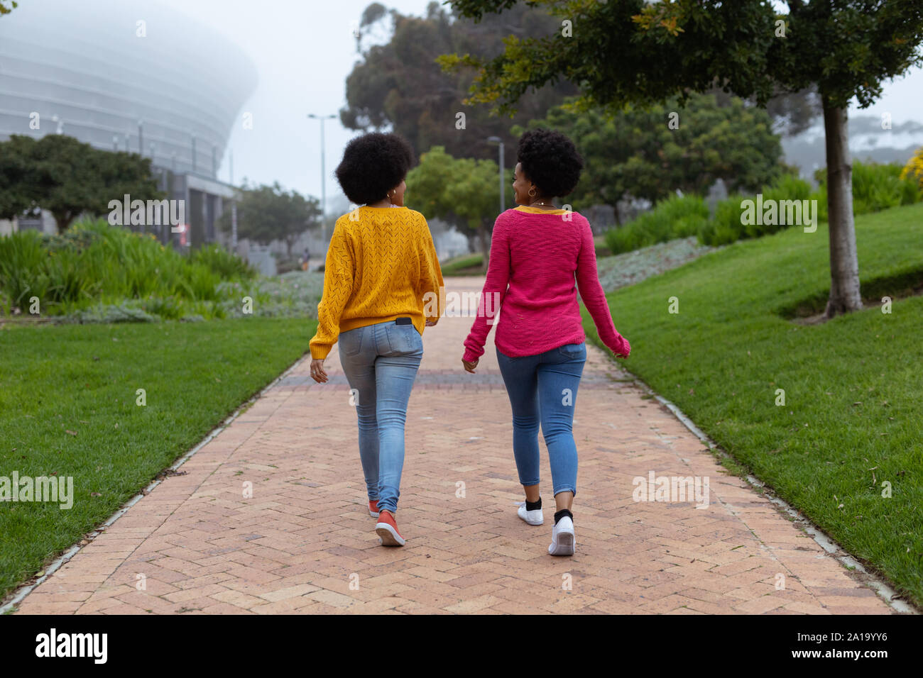 Two young women walking together in a park Stock Photo
